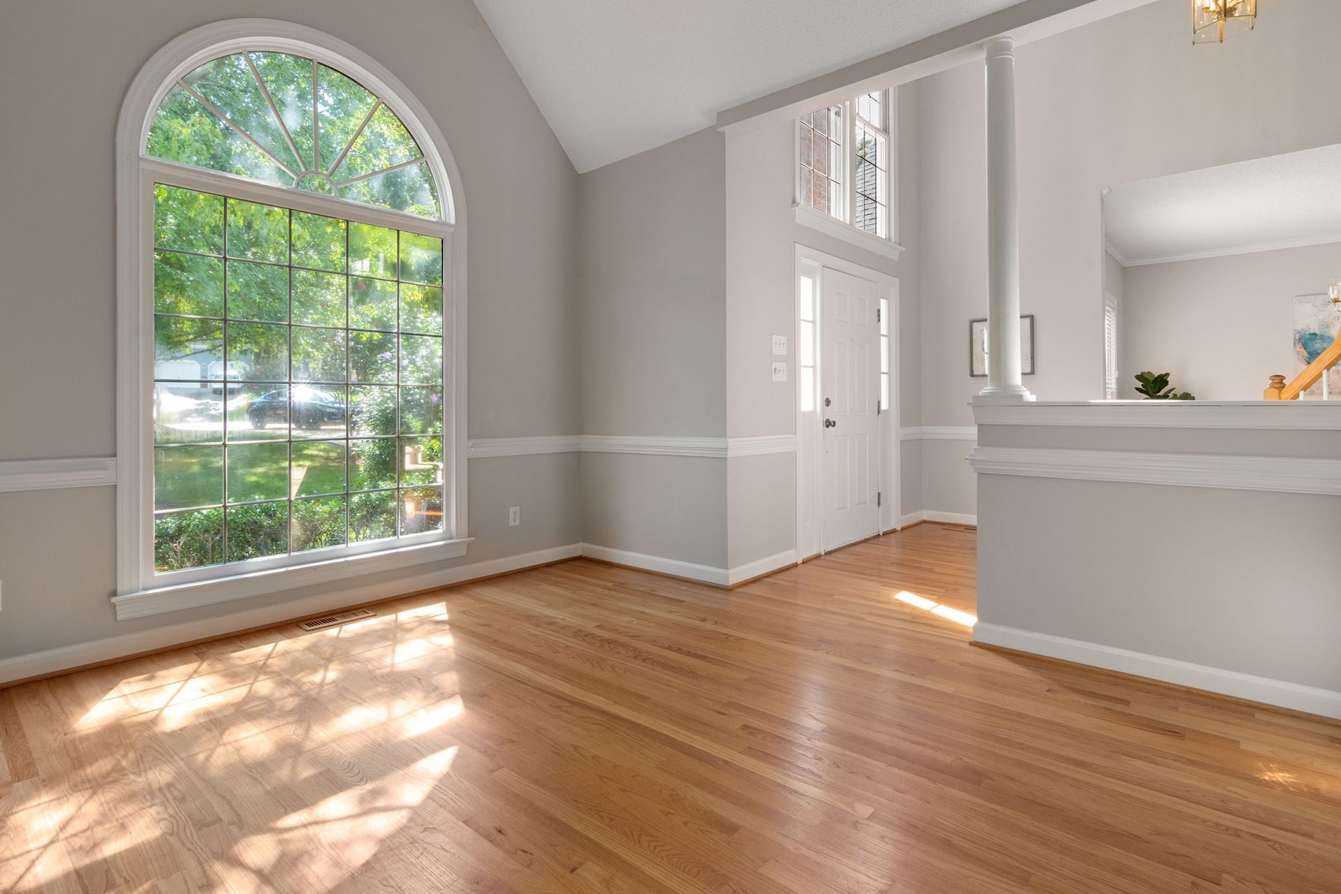 Bright living room with large window and hardwood floors, perfect for residential spaces.
